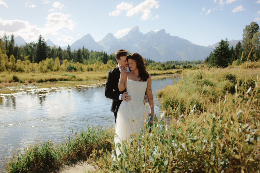 A bride and groom pose for a photo at Schwabacher Landing in Jackson Hole