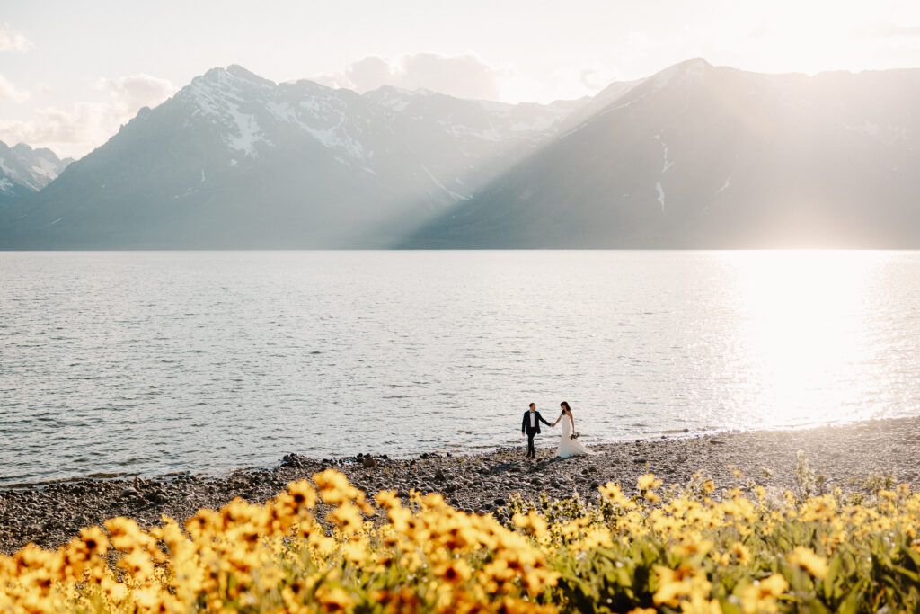 A couple walks along the lakefront at Couter Bay at their Jackson Hole elopement