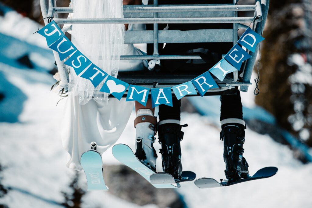 Newlyweds on ski lift with Just Married sign.