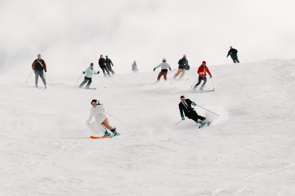 Newlyweds and guests skiing down mountain in Tetons ski wedding.