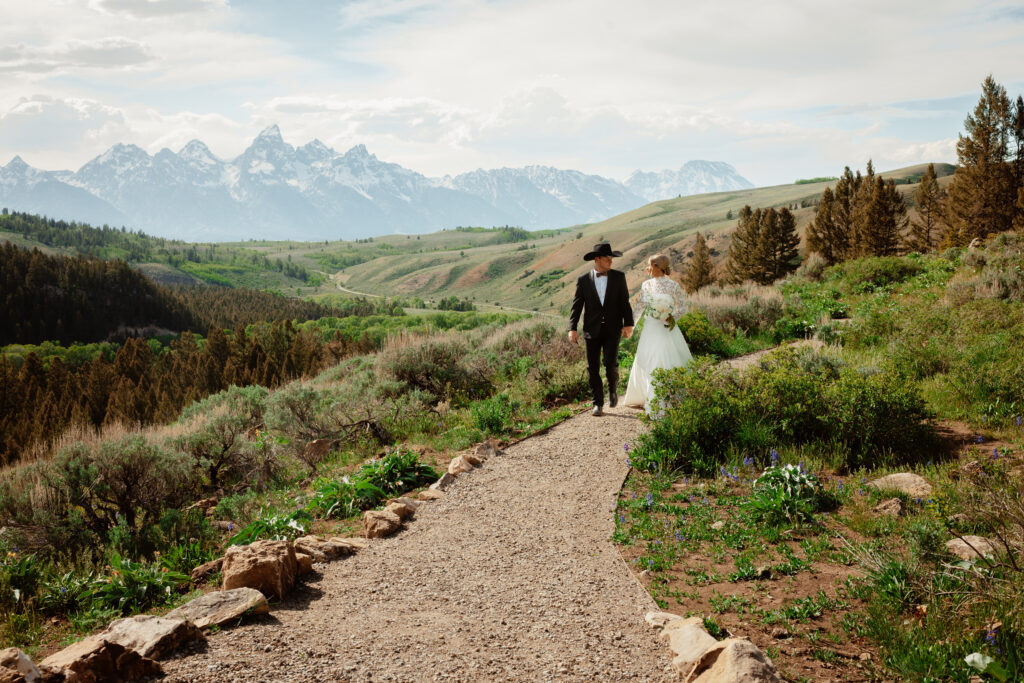 A bride and groom walk down a path at the Wedding Tree ceremony site in Jackson Hole